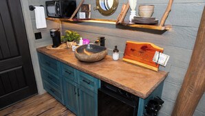 Una cocina con encimera de madera, un fregadero, un microondas y una cafetera.