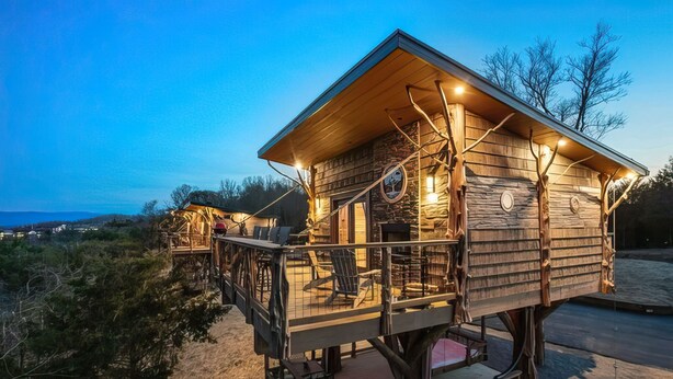 Une cabane en bois dotée d’un balcon, d’un espace extérieur aménagé pour s’asseoir et offrant une vue sur le paysage environnant.