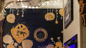 Une salle de bain avec un mur décoratif orné de motifs floraux et d’un miroir rond.