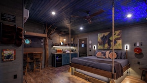 Een eenvoudige slaapkamer met een houten bed, een bureau en een stoel.