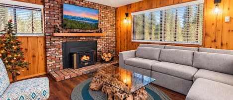 A living room with a fireplace, a sofa, a coffee table, and a Christmas tree.