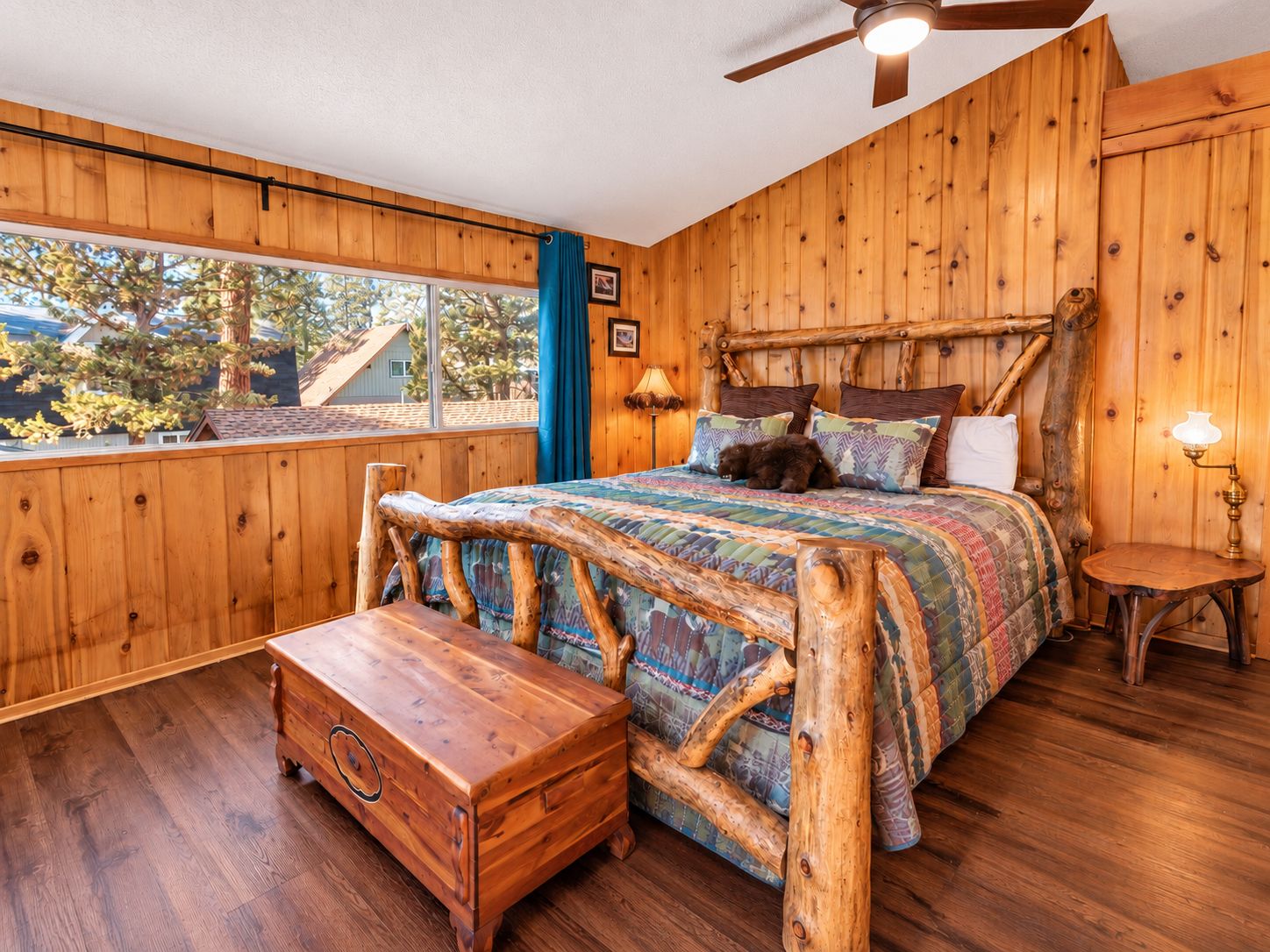 A wooden-themed bedroom with a bed, a nightstand, a bench, and a ceiling fan.