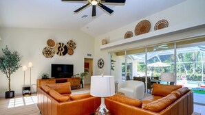 A spacious living room with a leather sofa, a TV, and decorative wall art.