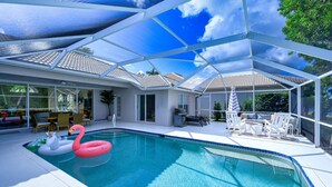 A covered swimming pool with inflatable toys, a barbecue area, and outdoor seating.