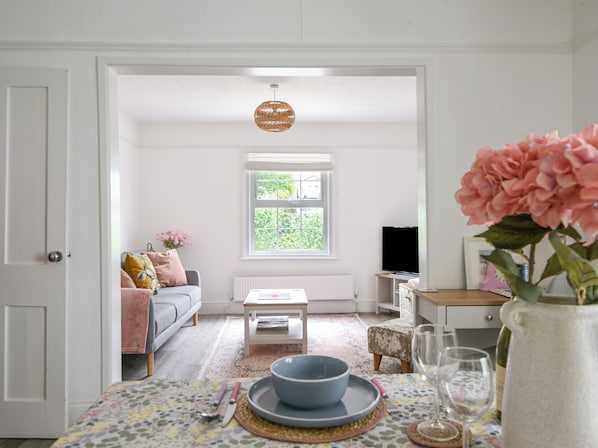 A cozy living room with a sofa, a coffee table, and a dining table set with a bowl and wine glass.