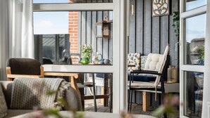 Een gezellig terras met een houten tafel, stoelen en een bakstenen muur.