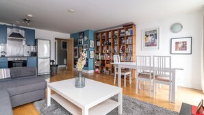 Una sala de estar moderna con un sofá gris, una mesa de centro blanca y una estantería llena de libros y objetos decorativos.