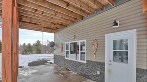 Une véranda couverte avec un plafond en bois et des fondations en pierre.