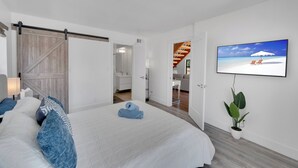 Et moderne hotelværelse med en stor seng, en skydedør, et fjernsyn og en potteplante.