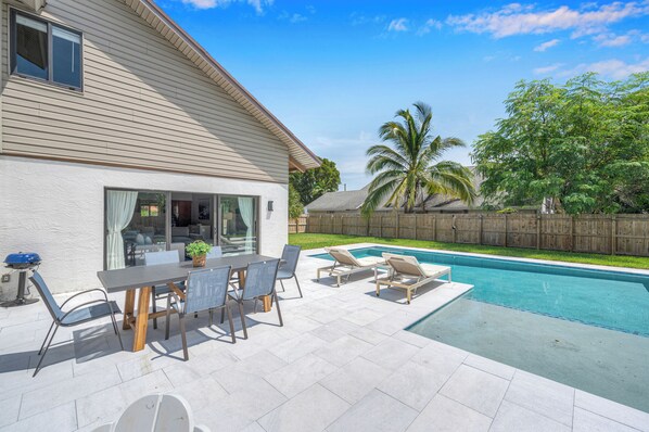 A backyard with a swimming pool, patio furniture, and a wooden fence. - Wonderful Tropical Pool House East Delray Near Ocean (Delray Beach)