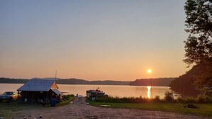 A dirt path leading to a small cabin by a lake at sunset. - Villa Dave (Gracefield)