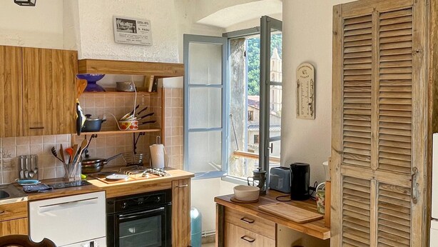 Eine Küche mit Holzausstattung, einem Geschirrspüler, einem Backofen und einem Fenster mit Blick auf Gebäude.