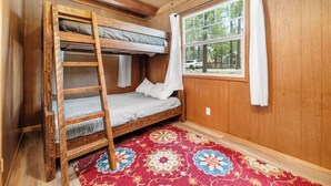 A bunk bed with a ladder, a window with curtains, and a patterned rug in a wooden room. - Finch Nest (Big Bear Lake)