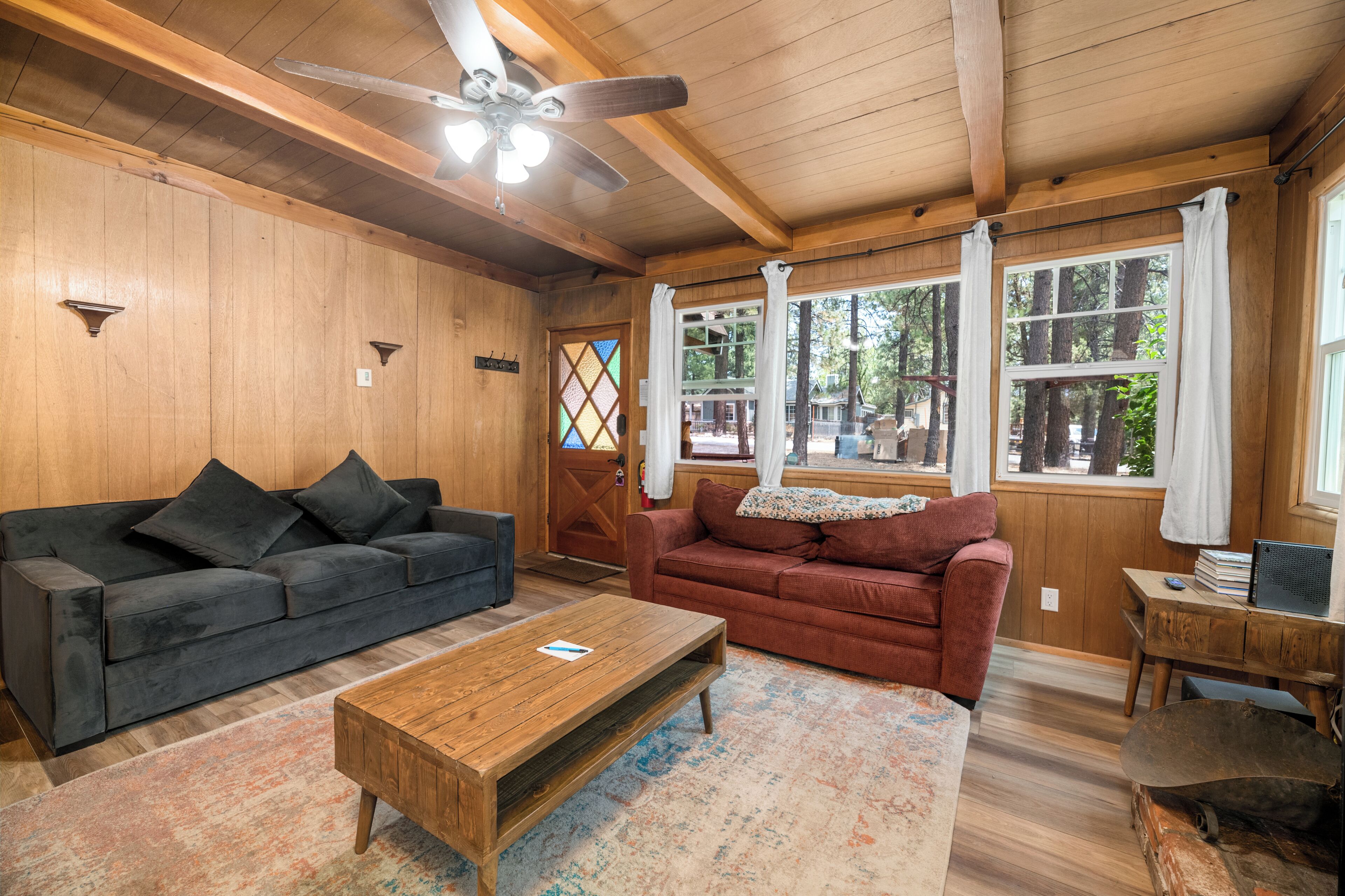A wooden-floored living room with two sofas, a coffee table, and a ceiling fan.
