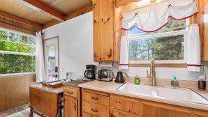 A wooden kitchen with a window, a sink, and a coffee maker. - Finch Nest (Big Bear Lake)