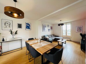 A modern living room with a wooden dining table, grey sofas, and artwork on the walls. - L'horizon - Spacieux et idyllique t3 (Poitiers)