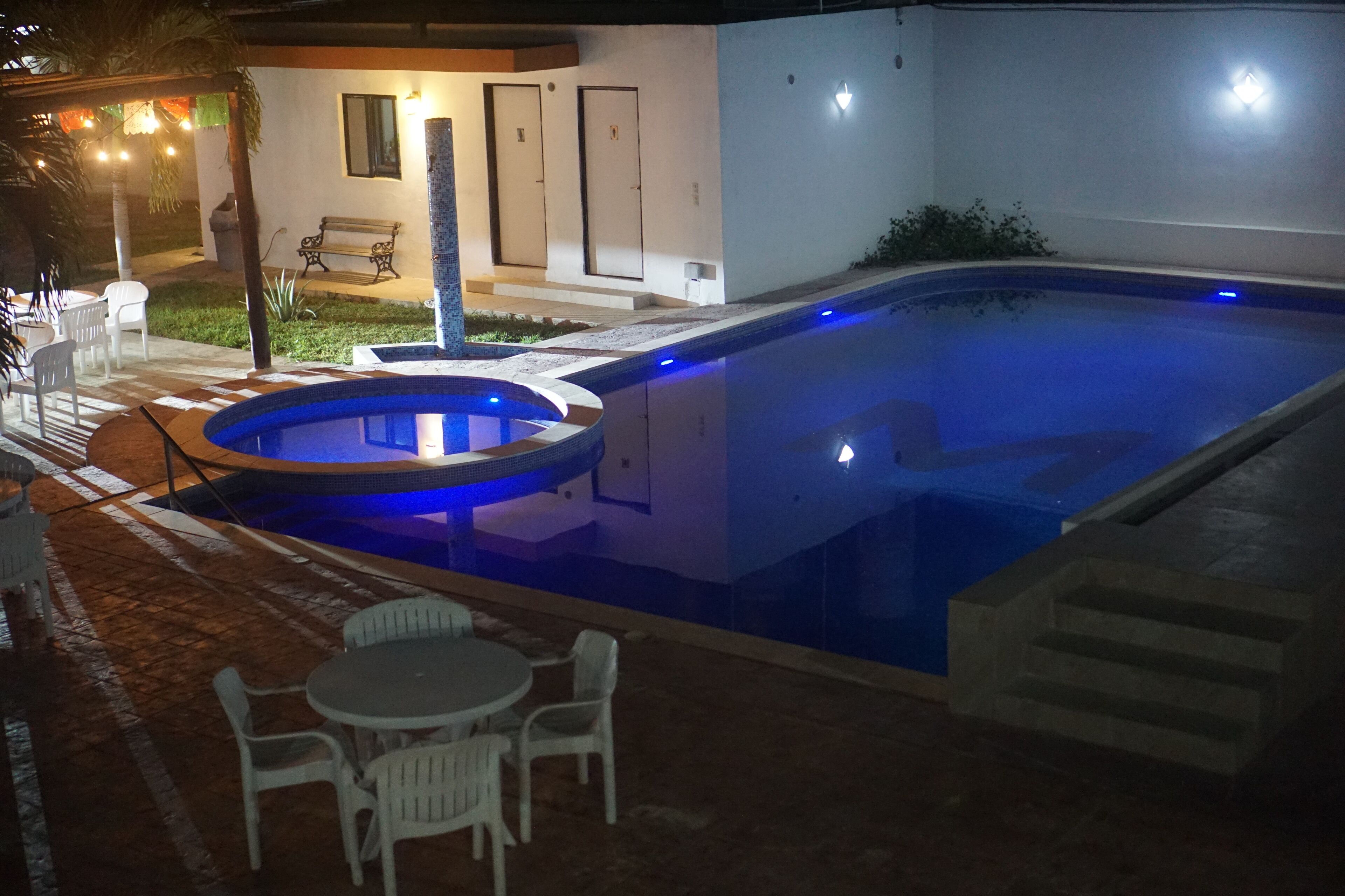 Una piscina amb una banyera d'hidromassatge, envoltada d'un espai exterior amb seients i una taula.