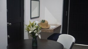 Ett runt bord med en vas med blommor och en hatt på en avställningsyta.