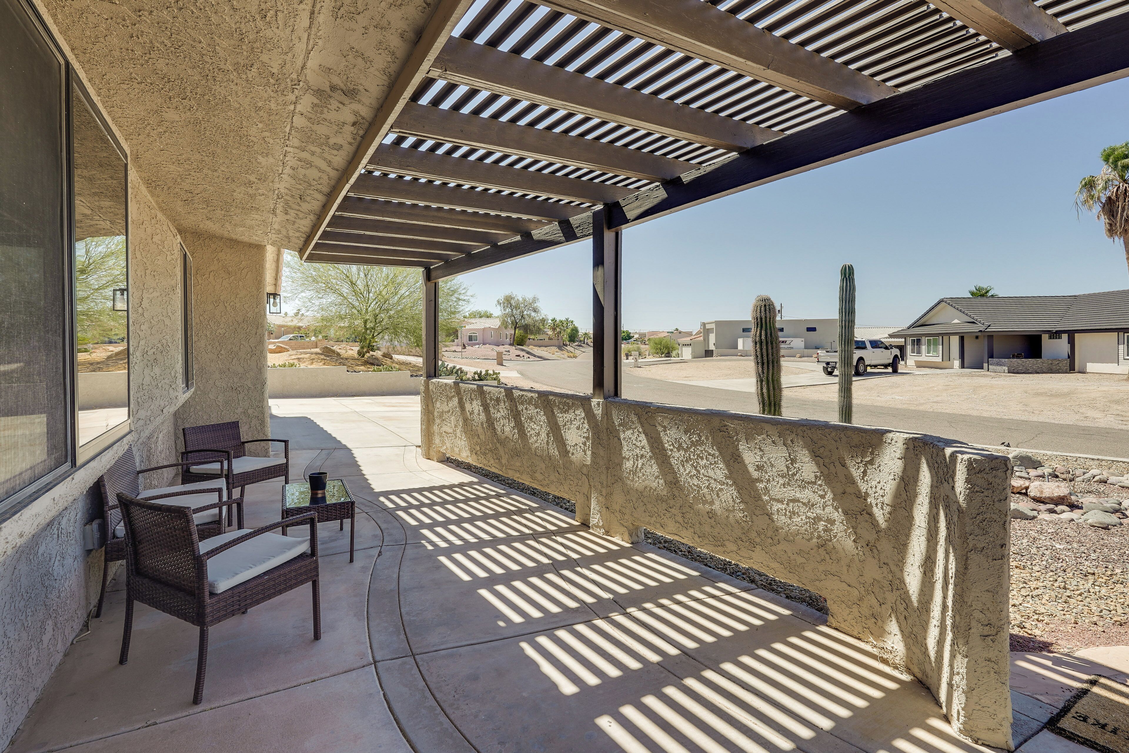 An outdoor patio with a pergola, seating, and a view of the surrounding area.