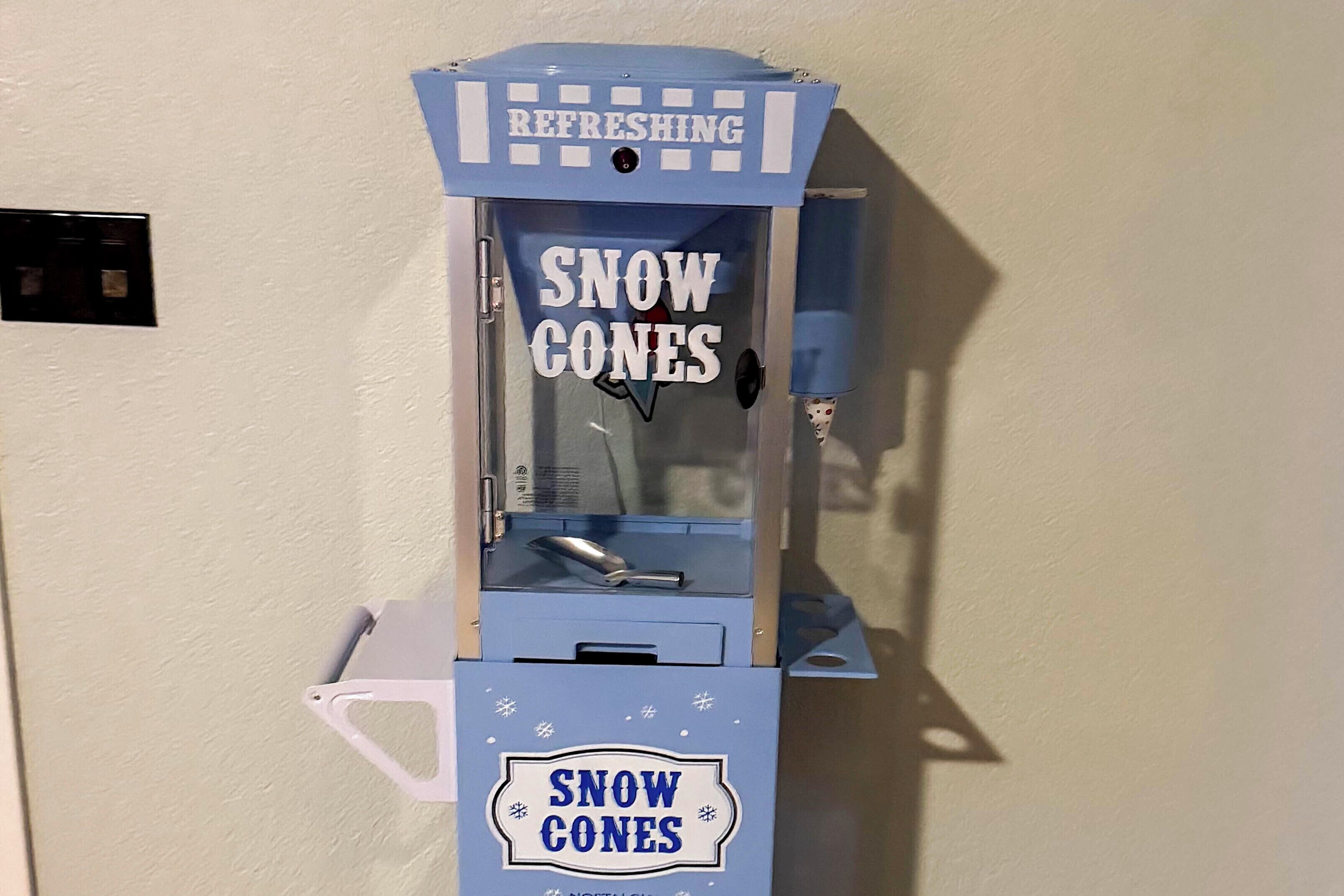 Ein Automat mit der Aufschrift 'SNOW CONES' und einem Schild mit dem Wort 'ERFRISCHEND'.