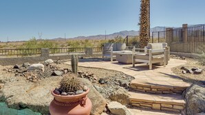 En udendørs terrasse med siddepladser, en kaktus og bjergudsigt.