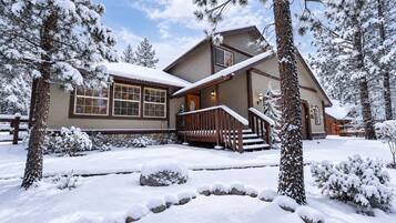 A two-story house with a wooden deck and a stone foundation.