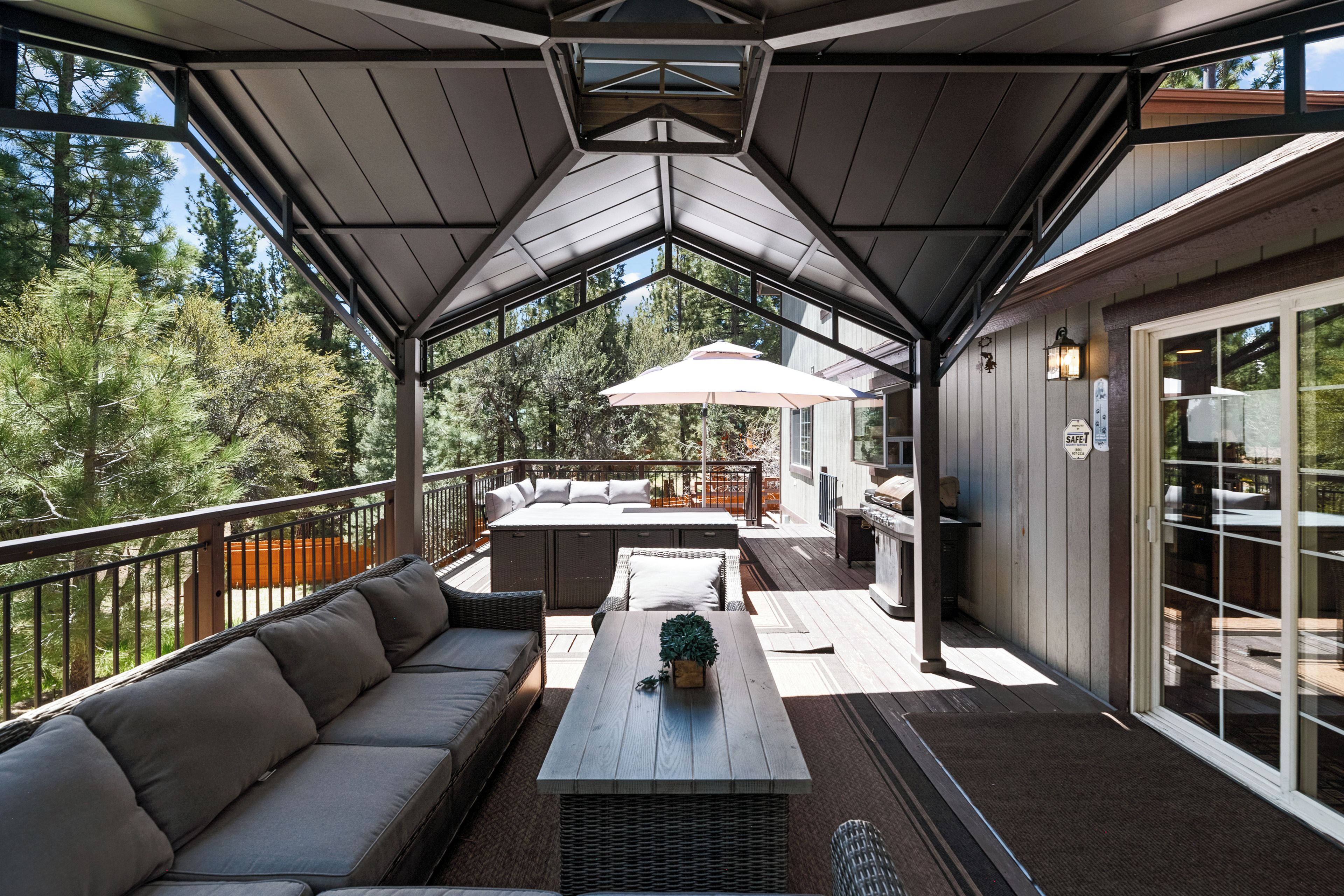 Un patio techado al aire libre con un sofá, una mesa y una sombrilla.