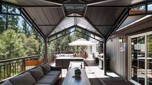 Eine überdachte Terrasse im Freien mit einer Couch, einem Tisch und einem Sonnenschirm.