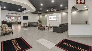 A modern hotel lobby with a reception desk, seating area, and a 'Welcome' mat. - Suburban Studios Salt Lake City Airport (Salt Lake City)