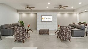 A modern living room with two sofas, a coffee table, and a television screen displaying the word "CHOICE". - Suburban Studios Salt Lake City Airport (Salt Lake City)