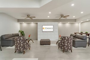 A modern living room with two sofas, a coffee table, and a television screen displaying the word "CHOICE".
