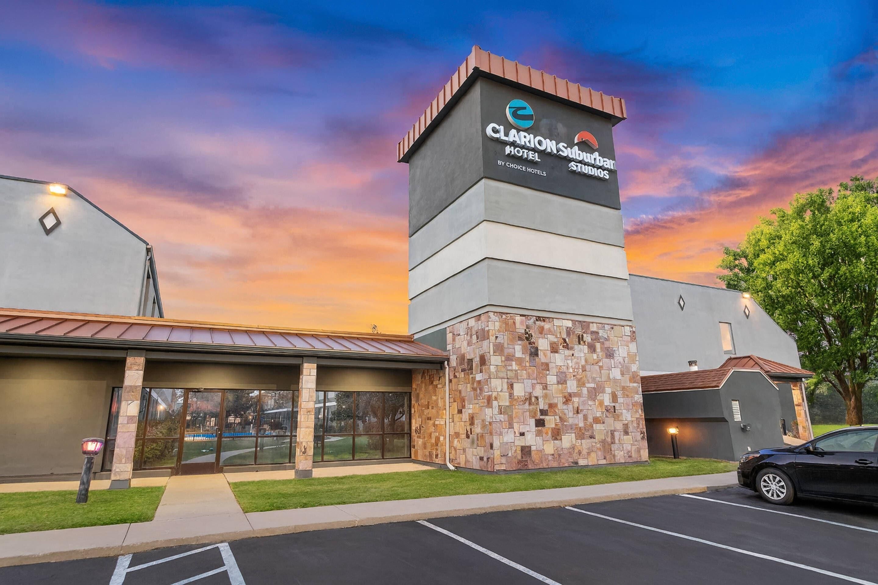 A hotel with a modern design, featuring a prominent tower with signage, a covered entrance, and a parking lot.