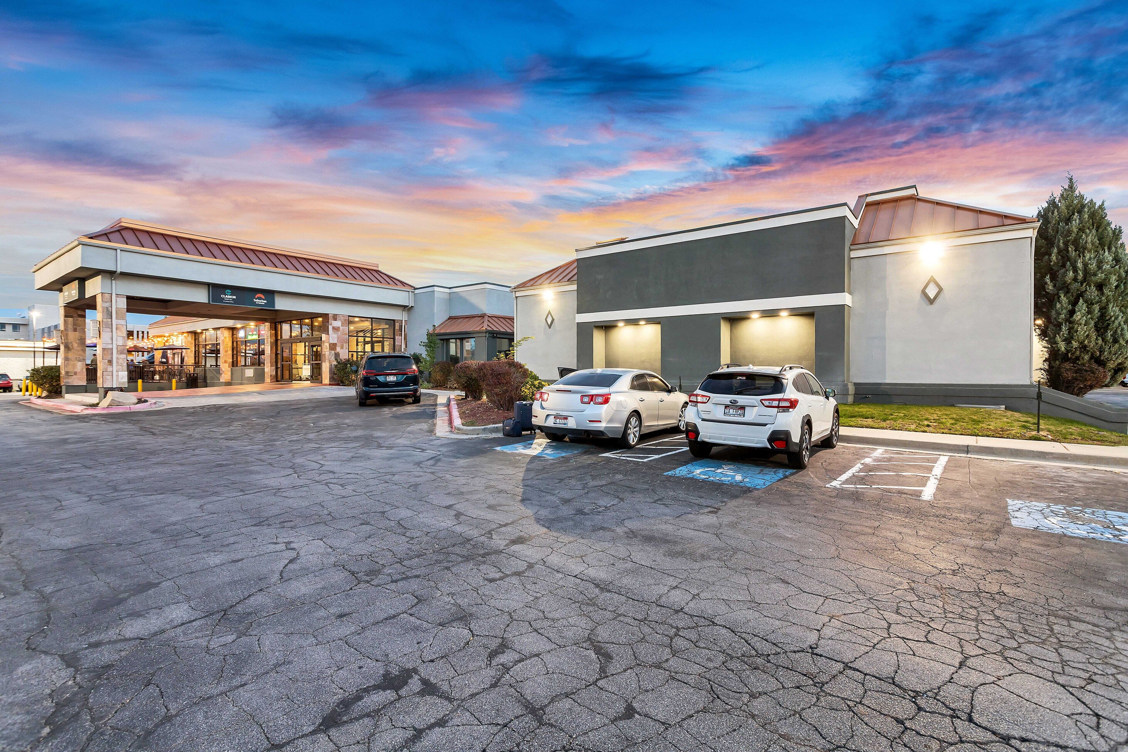 A hotel with a gas station, parking spaces, and a sunset sky.