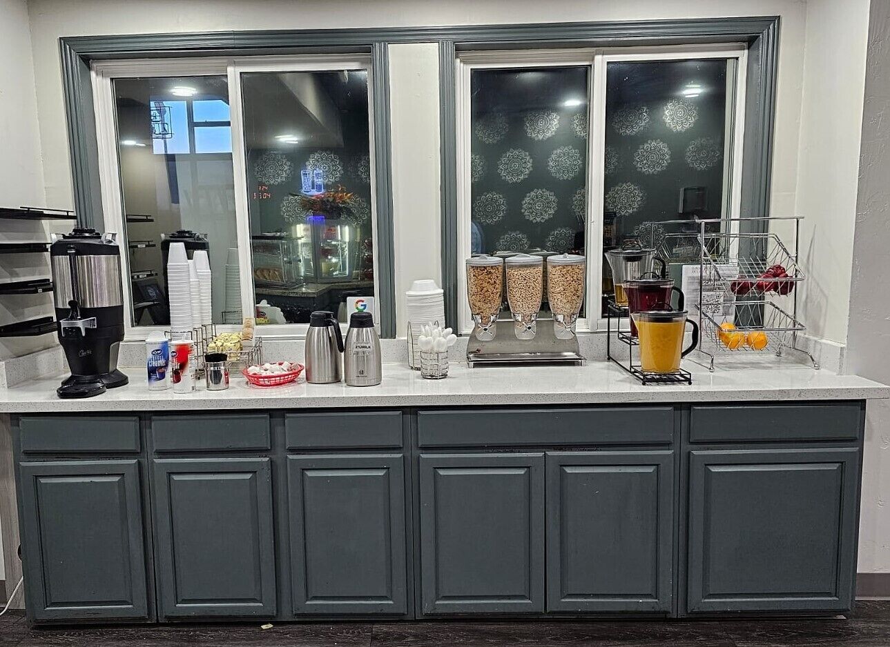 A kitchen counter with a coffee machine, sugar, coffee creamer, and a fruit basket.