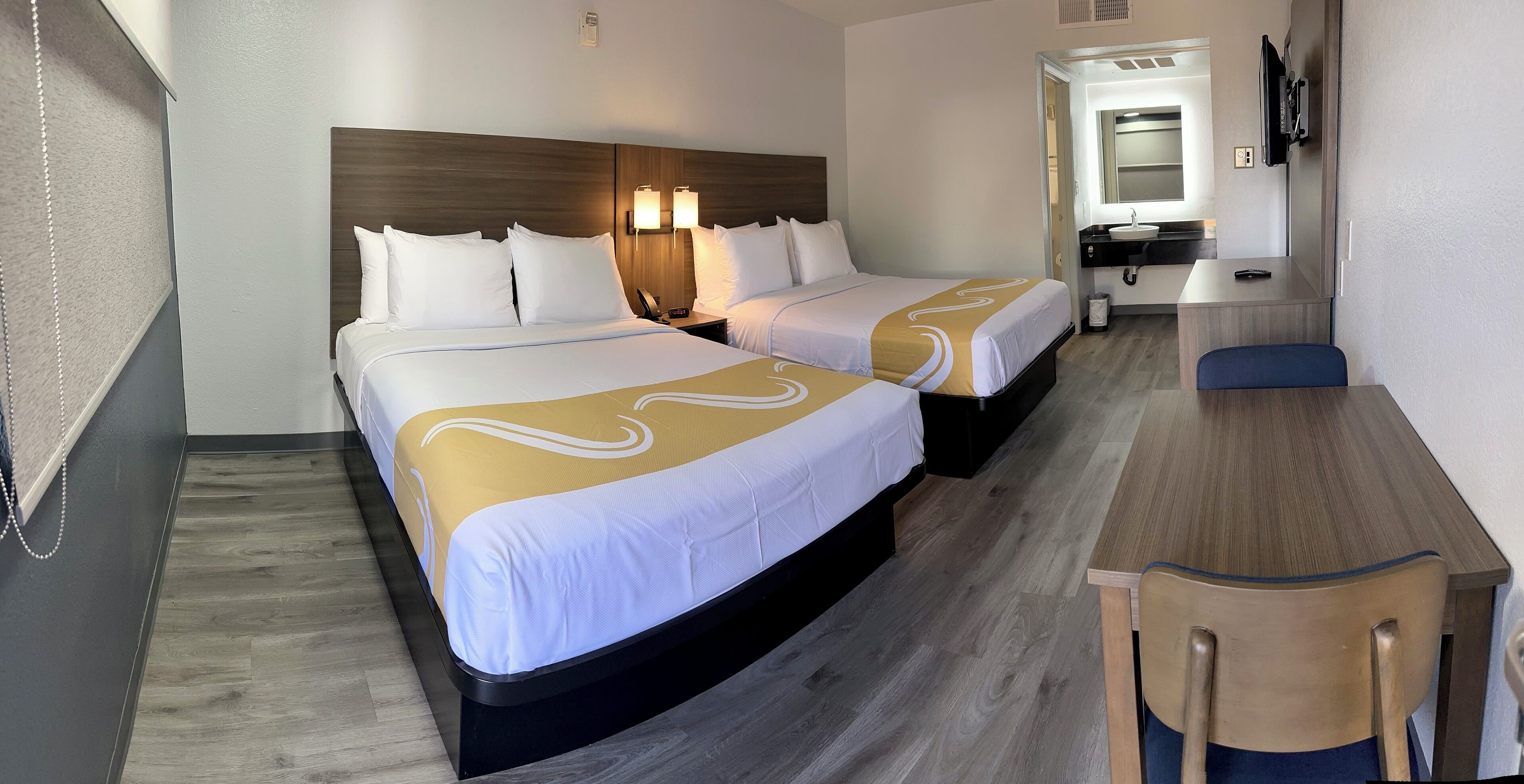 Ein Hotelzimmer mit zwei Betten, einem Schreibtisch und einem Spiegel.