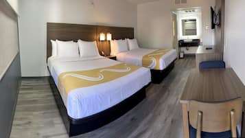 Una habitación de hotel con dos camas, un escritorio y un espejo.