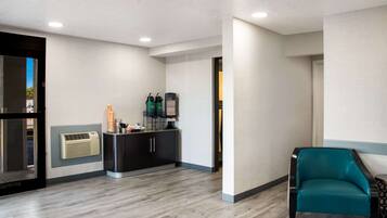 Un moderno vestíbulo de hotel con un mostrador de recepción, un sillón color turquesa y un equipo de aire acondicionado instalado en la pared.