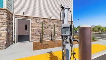 Una estación de carga para vehículos eléctricos PowerCharge frente a un edificio con paredes de piedra y una puerta.