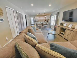 A living room with a sofa, a dining area, and a kitchen in the background. - Family friendly, Gameroom & Outdoor Space Close to Downtown & St Augustine Beach (St. Augustine)