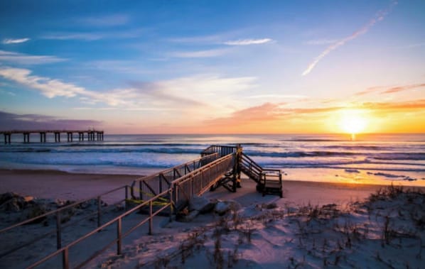 A beach with a wooden walkway leading to the ocean, a pier in the background, and a sunset. - Family friendly, Gameroom & Outdoor Space Close to Downtown & St Augustine Beach (St. Augustine)