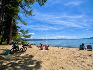 A beach with people sunbathing, a bicycle, and a boat in the background. - Snowflake Cabin | Walk to Beach | Dog Friendly (Tahoe Vista)
