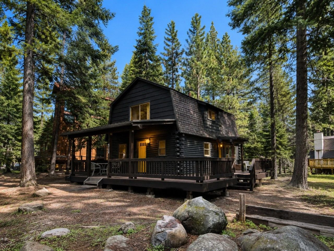 A cabin with a porch, surrounded by trees.