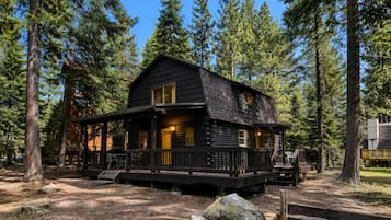 A cabin with a porch, surrounded by trees.