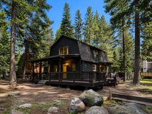 A cabin with a porch, surrounded by trees. - Snowflake Cabin | Walk to Beach | Dog Friendly (Tahoe Vista)