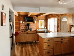 A cozy cabin-style kitchen with a fireplace, wooden cabinets, and a stone countertop. - Snowflake Cabin | Walk to Beach | Dog Friendly (Tahoe Vista)