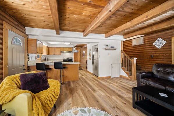 A log cabin interior with a kitchen, dining area, and living room.