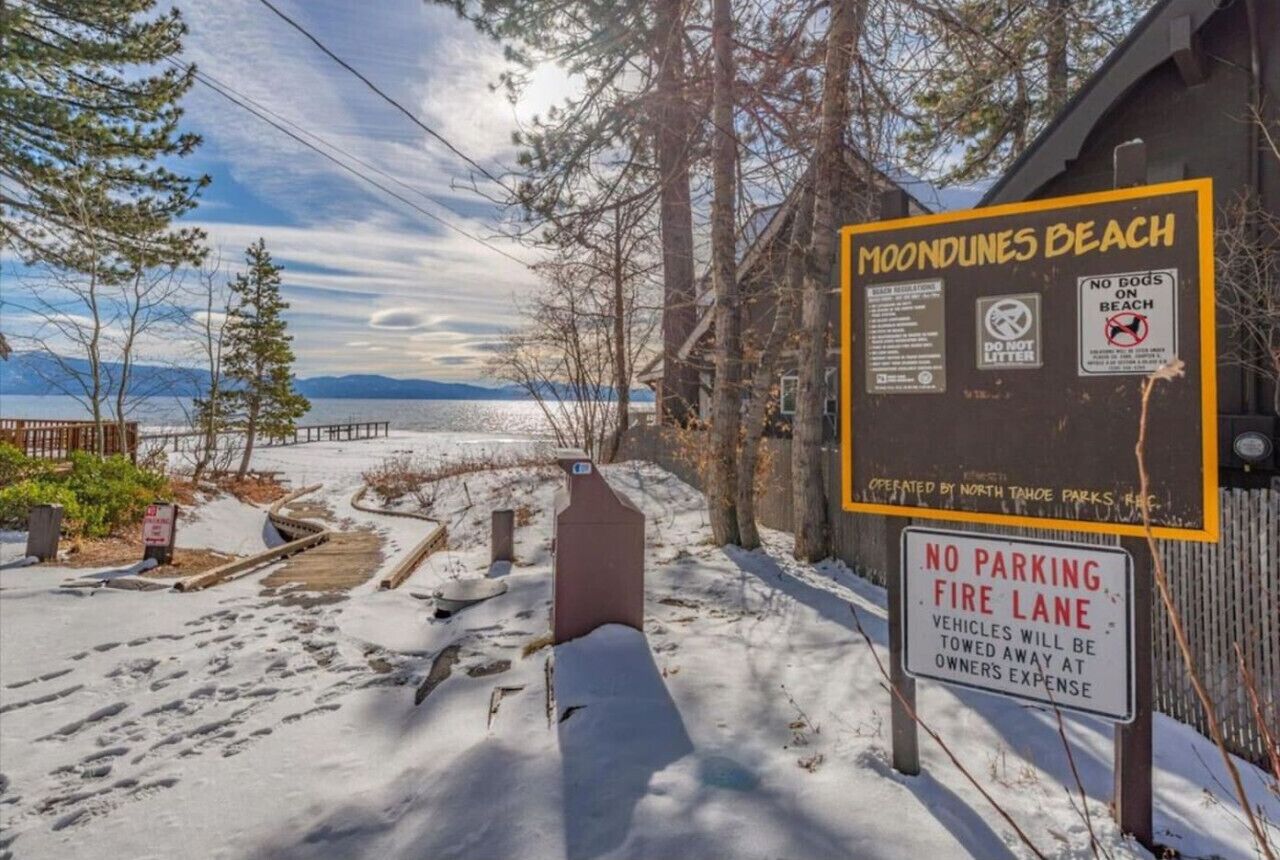 Un panneau indiquant l'accès à la plage de Moondunes, avec un panneau interdisant le stationnement sur la voie de circulation réservée aux véhicules d'urgence et un autre panneau interdisant l'accès aux chiens sur la plage.