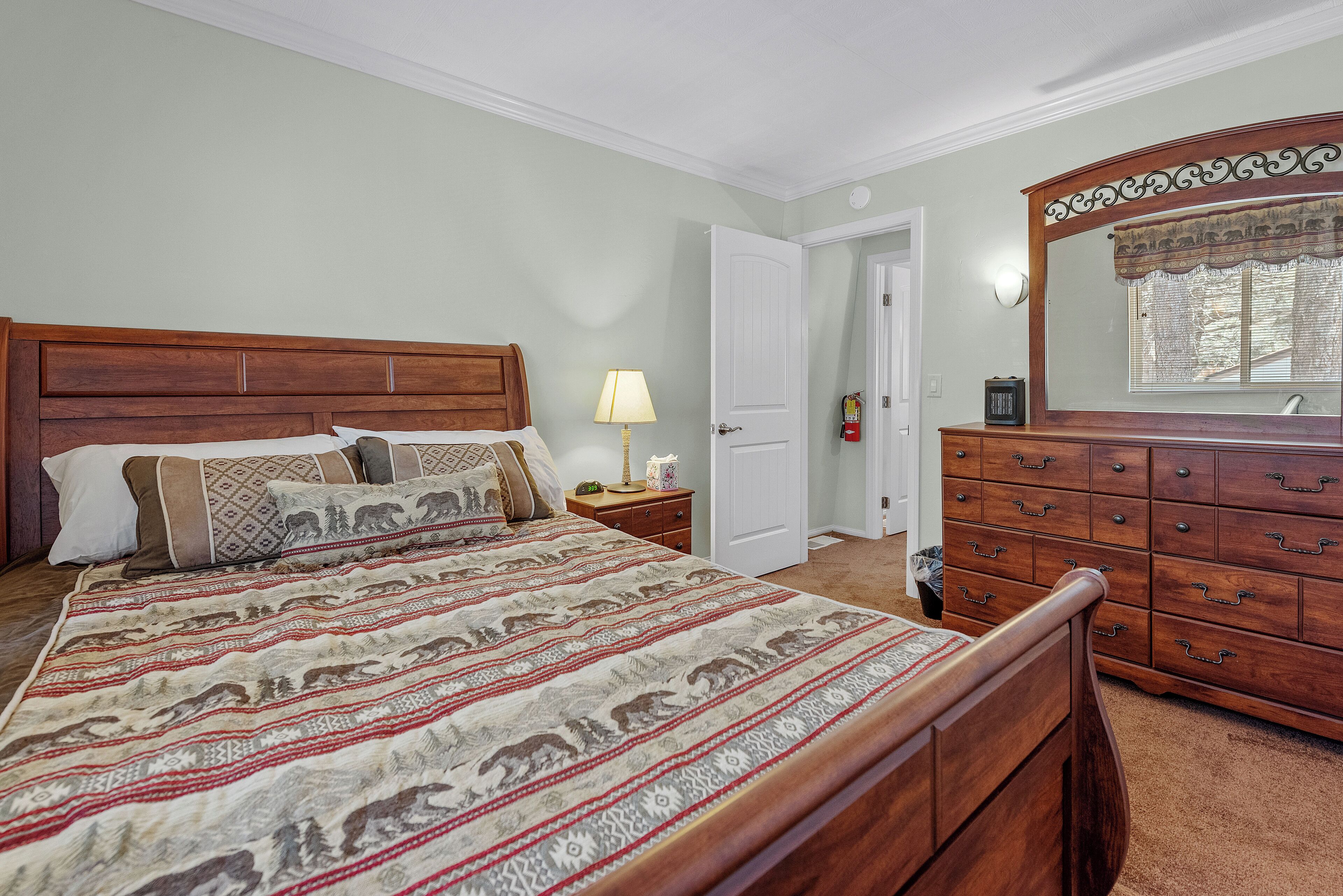 A bedroom with a wooden bed, a nightstand, a dresser, and a mirror.