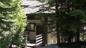 Una baita con una scala in legno che porta a una porta, immersa in una fitta foresta.