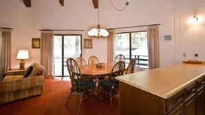 Un'area ristorazione con un tavolo e sedie in legno, un lampadario e vista attraverso le porte in vetro.